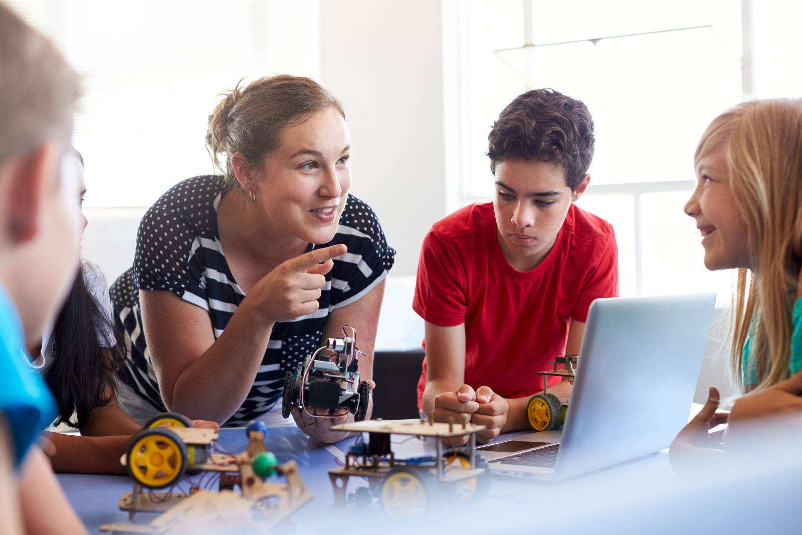 Students and teacher building robots with a laptop in a bright classroom